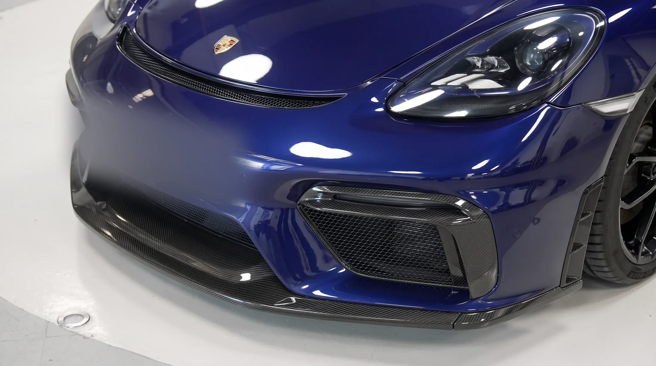 Fitment by Kynetik Koncepts — carbon fibre front splitter and intakes fitted to a blue Porsche