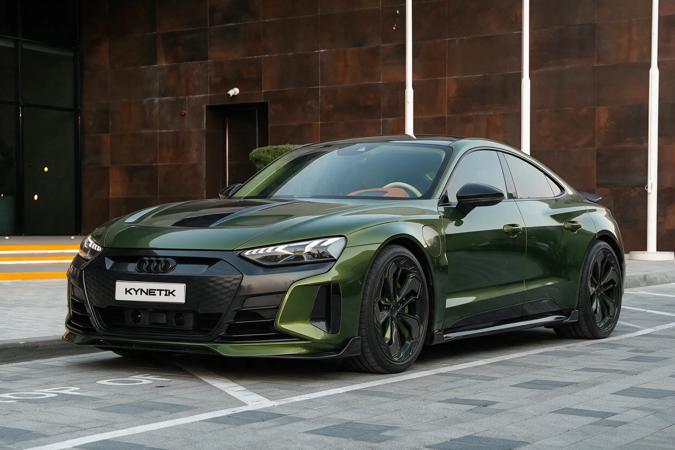 Audi RS e-tron GT by Kynetik Koncepts, green with a carbon fibre bonnet vent, front three-quarter outside the Dubai showroom