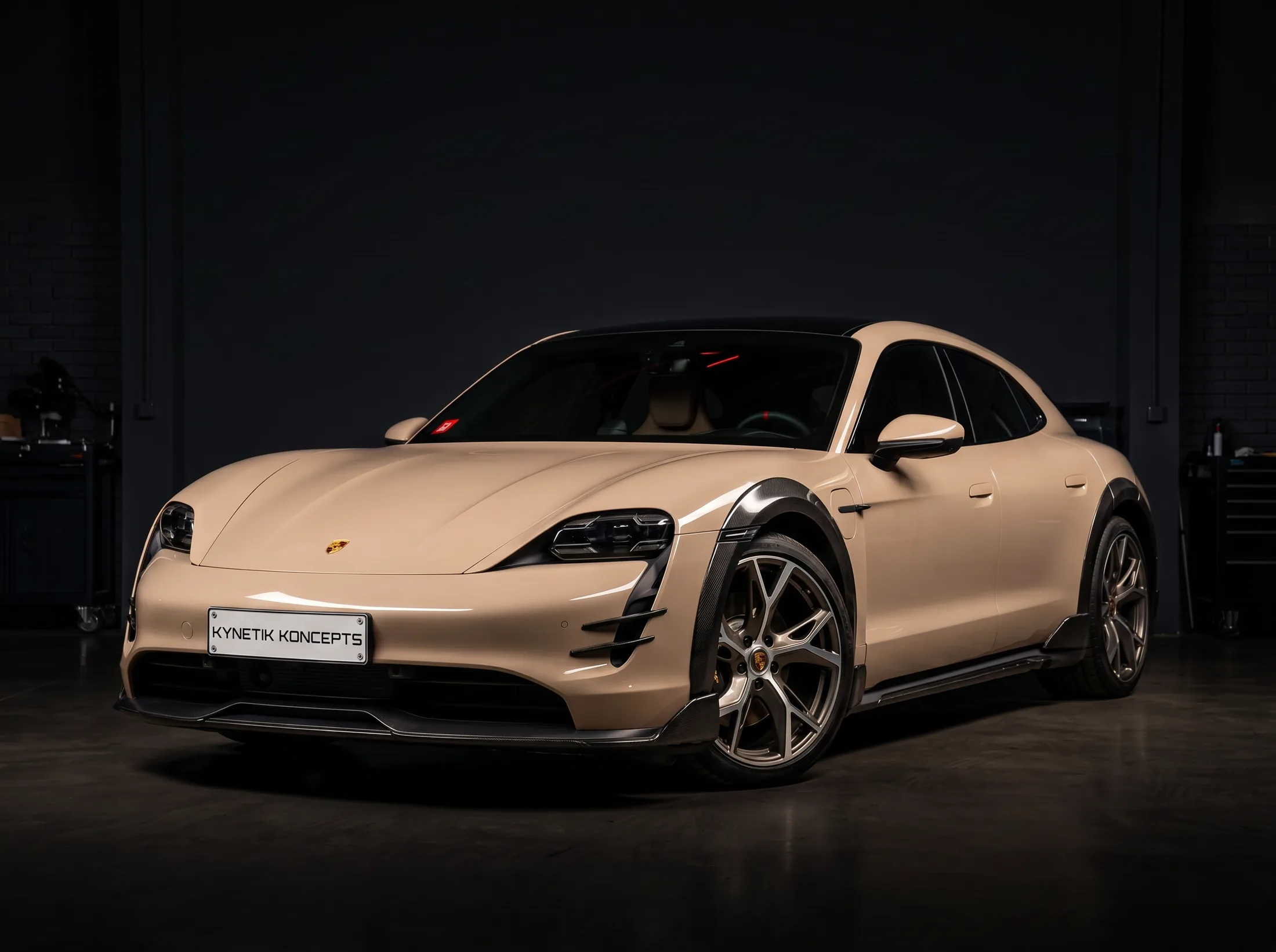 Porsche Taycan by Kynetik Koncepts — carbon fibre wide arches and side skirts, front three-quarter in the workshop