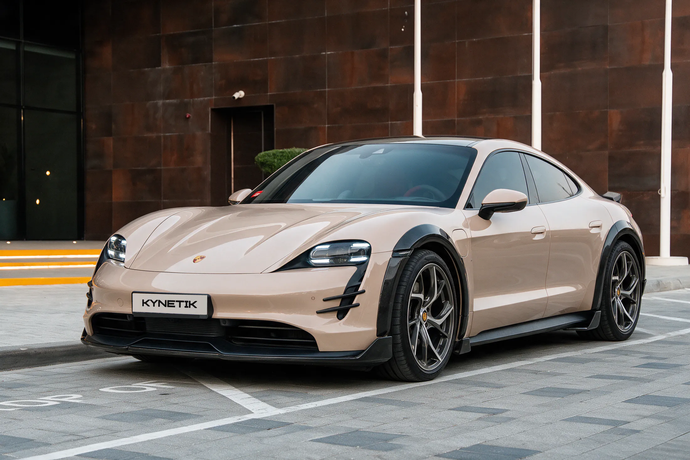 Porsche Taycan by Kynetik Koncepts, carbon fibre wide arches and front splitter, front three-quarter outside the Dubai showroom